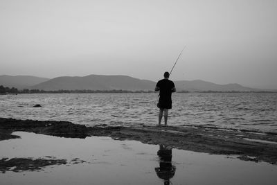 Rear view of man fishing in lake