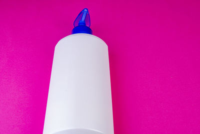 Close-up of pink bottles on table against wall