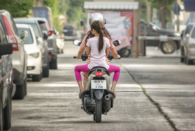 Rear view of woman riding motorcycle on street