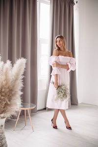 Full length portrait of woman standing against wall