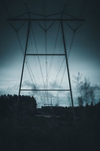 Low angle view of silhouette electricity pylon on field against sky