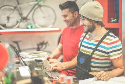 Smiling mechanics working on laptop in auto repair shop