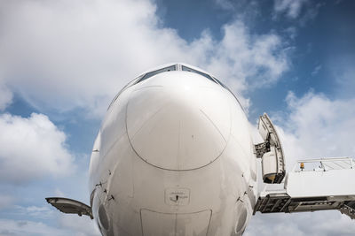 Detail shot of an airplane nose against clouds