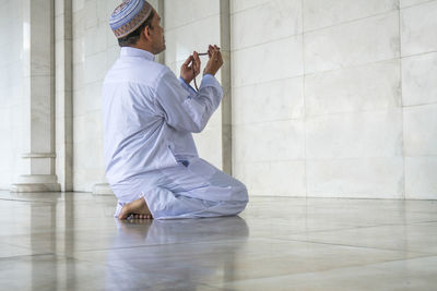 Man holding prayer beads while praying at mosque