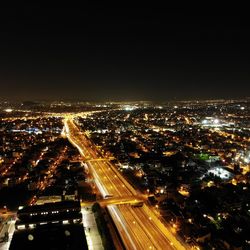 High angle view of illuminated street amidst buildings in city at night