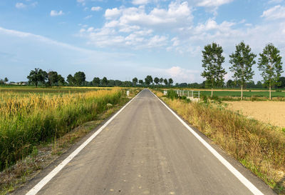 Road amidst field against sky