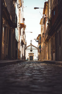 Narrow street amidst buildings in city against sky