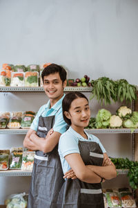 Portrait of young woman standing by food at market stall