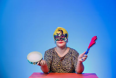 A jewish woman in a headdress and carnival mask controls the noise on purim while reading