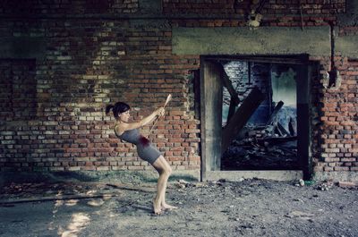 Digital compromise image of young woman killing herself with arrow by abandoned building