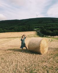 Woman standing by hay on field