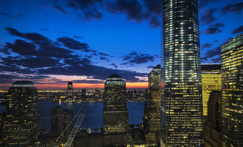 Illuminated buildings in city against sky at dusk