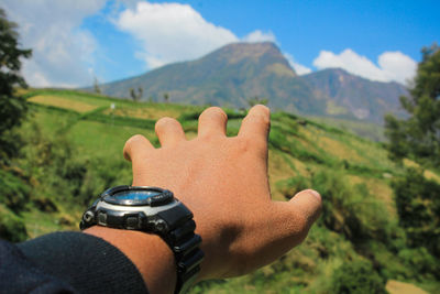 Cropped hand of man against mountain range