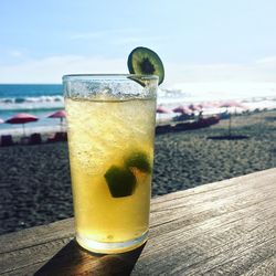 Close-up of fresh lemon drink on table at beach against sky