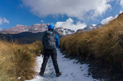 Rear view of man standing on snowcapped mountain