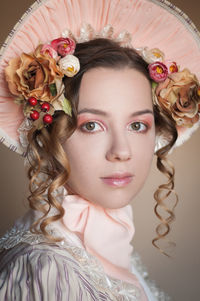 Close-up portrait of beautiful young woman wearing flowers and hat