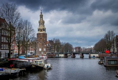 Boats in canal by buildings against sky in city