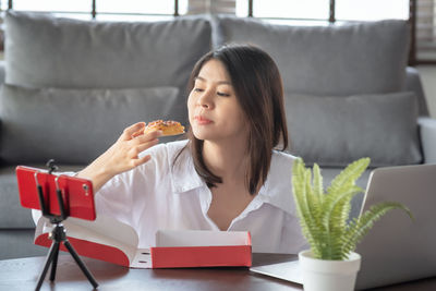 Young woman using phone while sitting on table