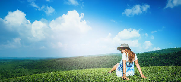 Rear view of woman standing on field against sky