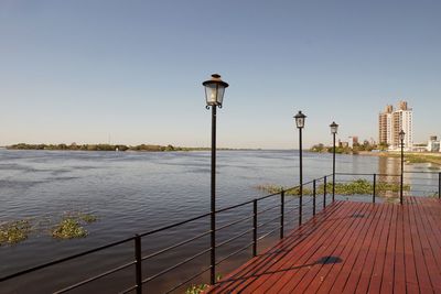 Promenade by sea against clear sky