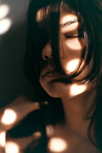 Close-up of young woman with eyes closed against wall