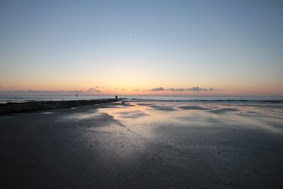 Scenic view of beach against clear sky during sunset