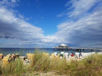 People on beach against cloudy sky