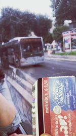 Close-up of person reading book against bus