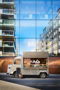 Male owners in food truck parked on city street against glass building