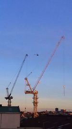 Cranes at construction site against blue sky