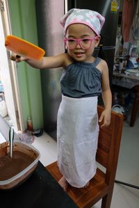 Full length of girl holding lid while standing on chair