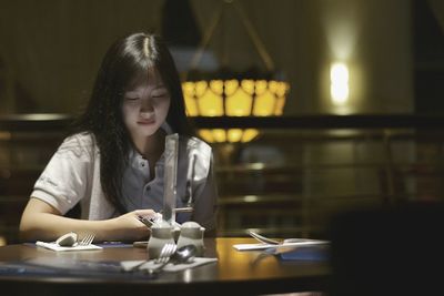 Young woman using phone on restaurant table