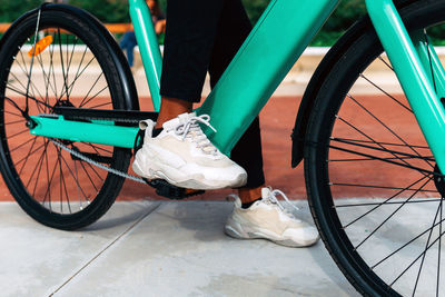 Crop unrecognizable ethnic male riding contemporary bike along street in city