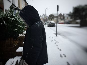 Rear view of woman walking on road in winter