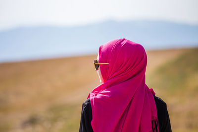 Rear view of woman standing against purple sky