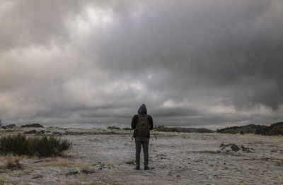 Rear view of adult man on top of mountain against cloudy sky, in tejera negra, guadalajara, spain