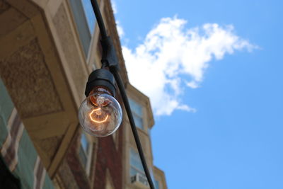 Low angle view of illuminated light bulb against sky