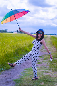 Portrait of smiling young woman holding umbrella standing on land
