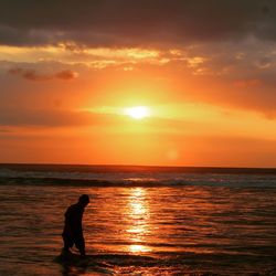 A man in sea against orange sky at kuta beach in bali. you can enjoyed your summer day in here