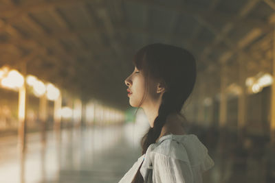 Young woman with eyes closed standing in corridor