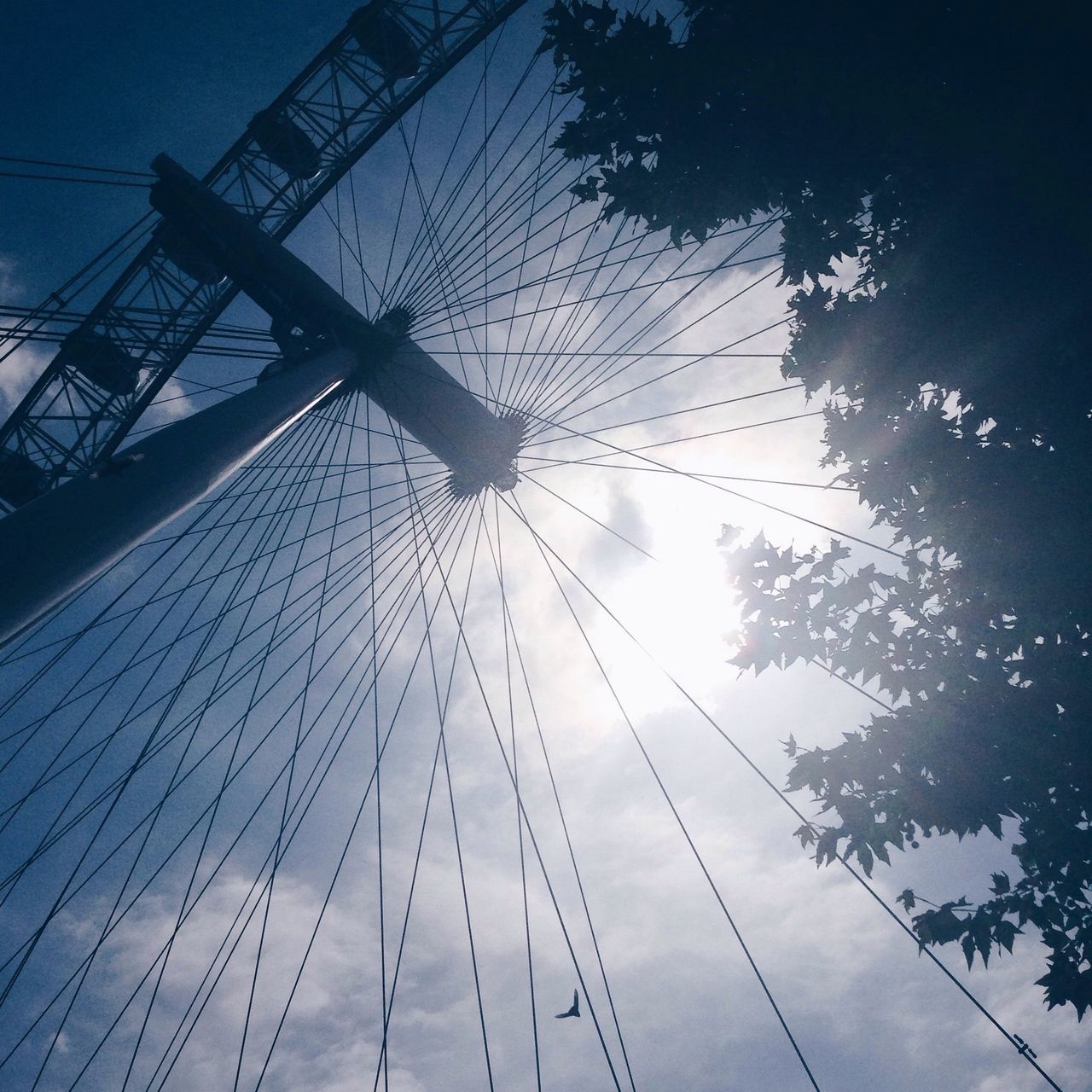 low angle view, sky, sunlight, amusement park, silhouette, sun, clear sky, outdoors, amusement park ride, blue, ferris wheel, day, arts culture and entertainment, electricity pylon, no people, fuel and power generation, electricity, sunbeam, nature, part of