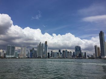 City at waterfront against cloudy sky