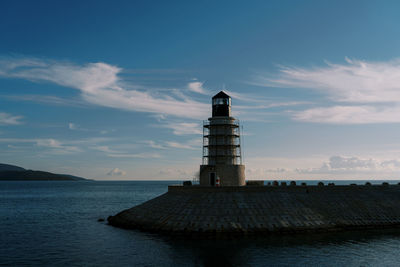 Lighthouse by sea against sky