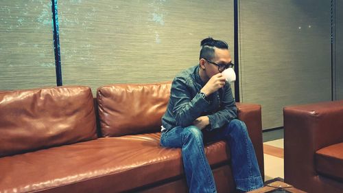 Full length of man sitting on sofa