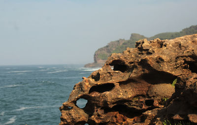 Close-up of rock by sea against clear sky