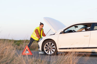 Side view of man standing in car