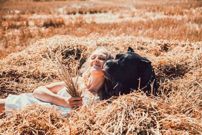 Woman with dog relaxing on hay