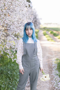 Portrait of beautiful woman standing by flower plants