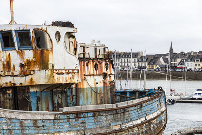 Abandoned boat moored in water against sky