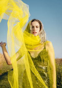 Portrait of a beautiful young woman against yellow sky